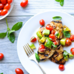 Grilled chicken, cherry tomatoes, and chopped avocado on a plate.