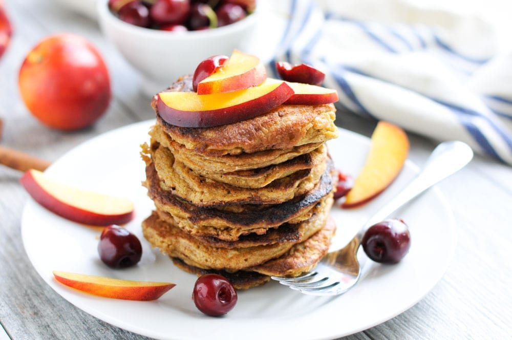 A stack of Oatmeal Pancakes with Nectarines and Cherries on top. 