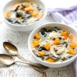 two white bowls of slow cooker chicken kale and sweet potato soup with spoons on white table