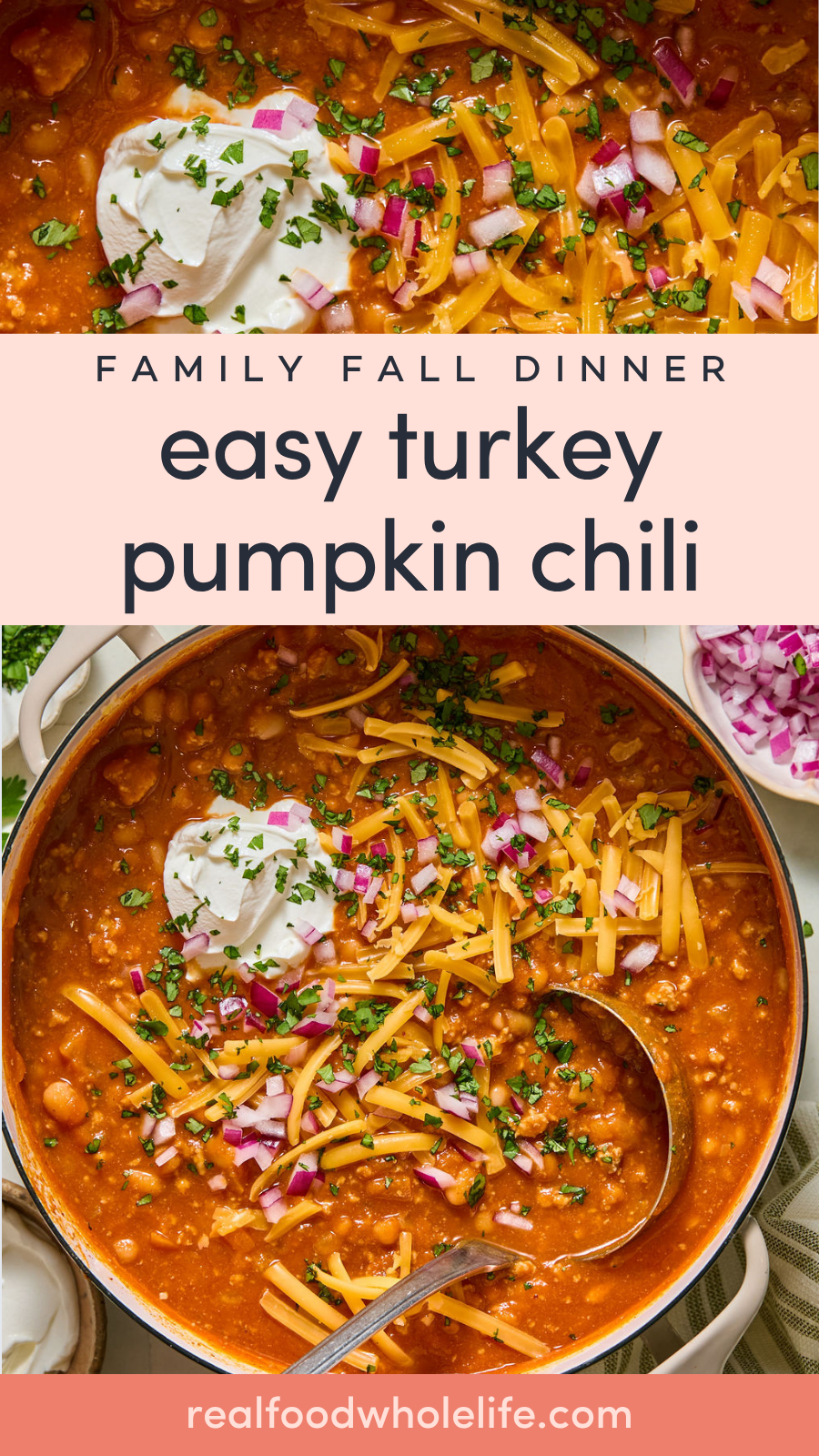 A pot of turkey pumpkin chili topped with sour cream, shredded cheese, chopped red onion, and herbs, with a spoon inside.