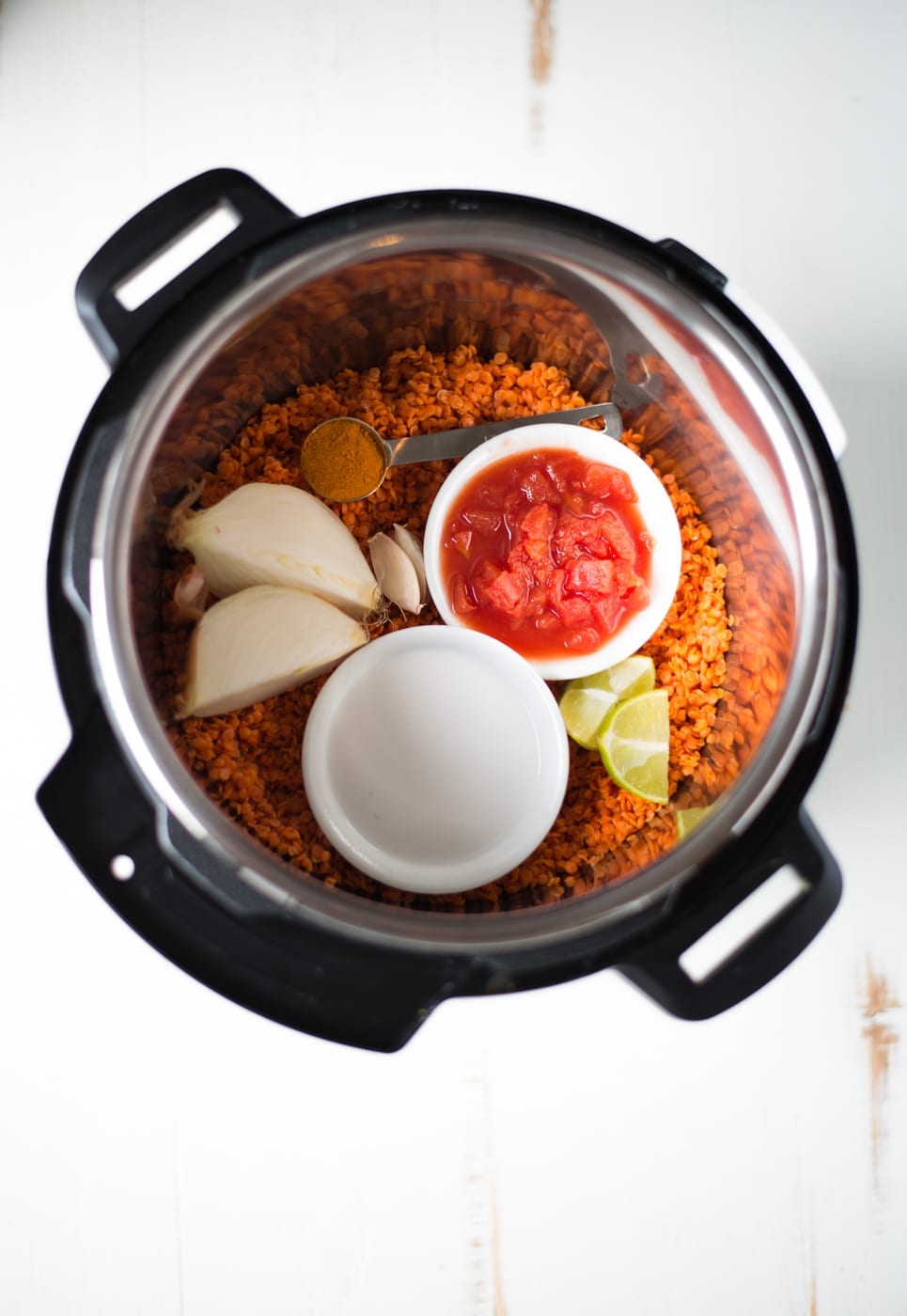 Overhead shot of red lentils, tomatoes, coconut milk, onion, and spices in an Instant Pot.