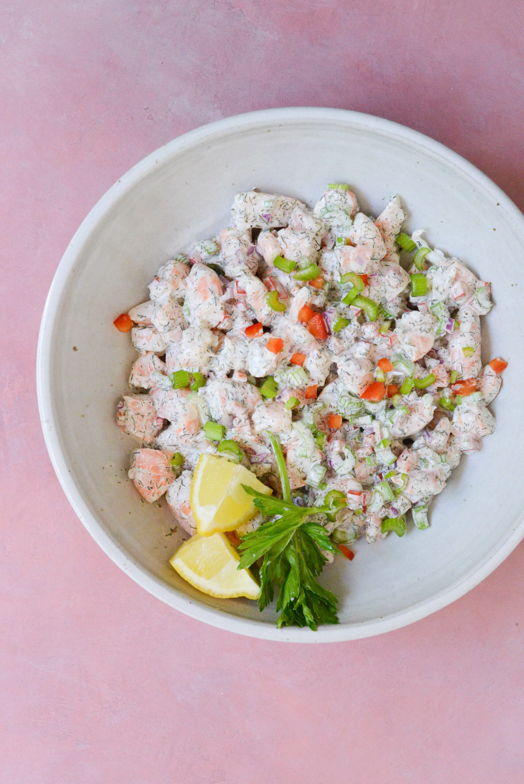 A large bowl filled with creamy chopped shrimp, celery, and bell peppers.