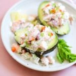close up of two shrimp stuffed avocado halves on a white plate