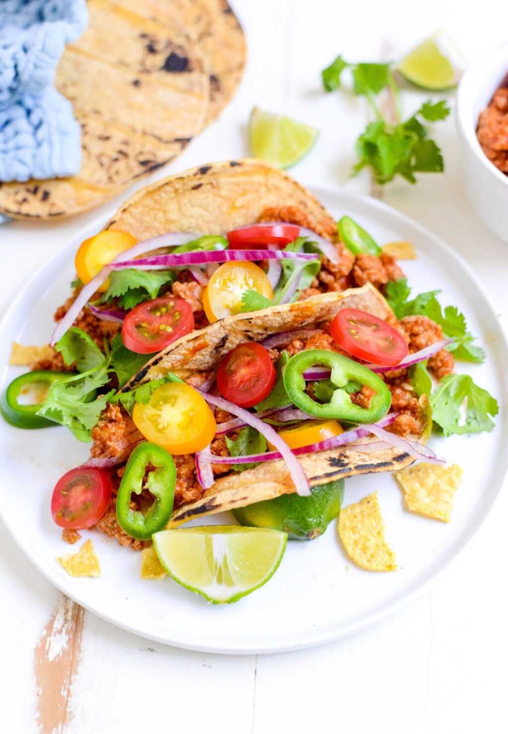 two slow cooker turkey tacos on a white plate with cilantro and lime wedges