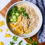 white bowl of crockpot white chicken chili with jalapenos and tortilla chips on top