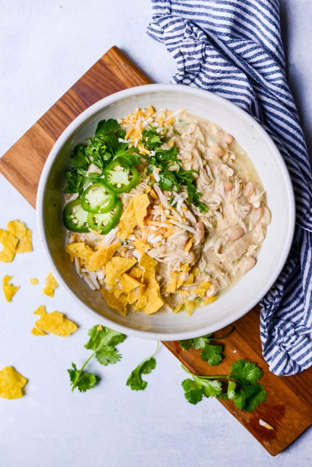 white bowl of crockpot white chicken chili with jalapenos and tortilla chips on top