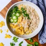 white bowl of crockpot white chicken chili with jalapenos and tortilla chips on top