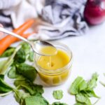 spoon full of apple cider vinaigrette dipping into a glass jar