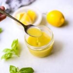 easy lemon vinaigrette dressing in a glass mason jar with a spoon and fresh herbs