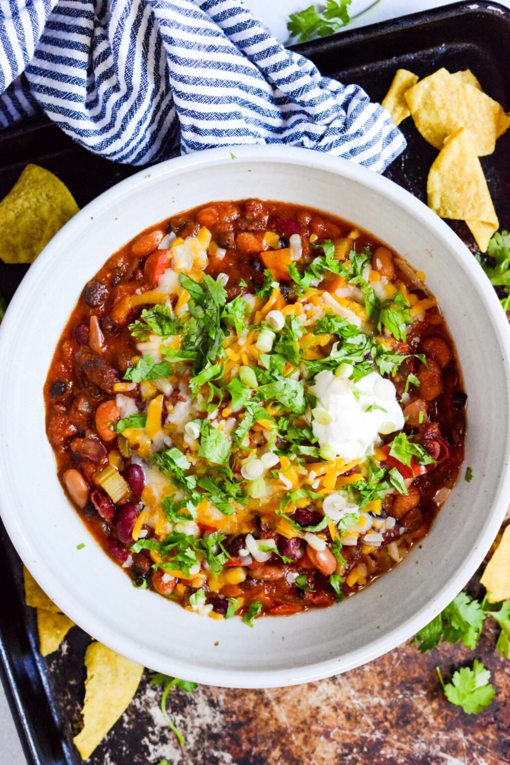 close up of crockpot vegetarian chili in a white bowl with toppings