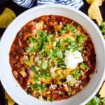 close up of crockpot vegetarian chili in a white bowl with toppings