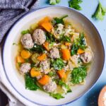 white bowl filled with soup with a blue background and fresh herbs