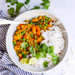 white bowl filled with slow cooker vegetable curry with a striped blue napkin on the side