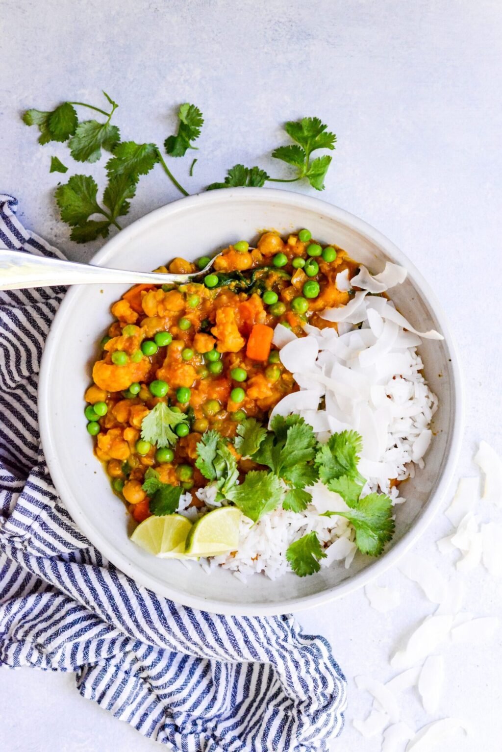 white bowl filled with slow cooker vegetable curry with a striped blue napkin on the side