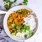 white bowl filled with slow cooker vegetable curry with a striped blue napkin on the side
