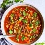 top down view of white bowl of vegetable soup with striped blue napkin