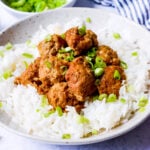 white bowl with chicken meatballs served over white rice on a blue background