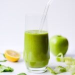 Green lettuce smoothie in a glass with a glass straw.