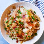 white bowl filled with slow cooker cabbage with a striped napkin on a blue background