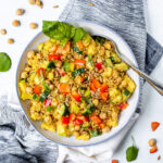 Overhead shot of blue and white bowl on a white background filled with quinoa, chopped veggies, chickpeas, and basil.