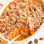 Overhead shot of sweet potato casserole with pecan topping with a serving spoon.