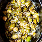 Overhead shot of cooked Brussel sprouts with parmesan in a slow cooker.