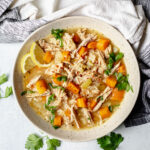 Overhead shot of turkey rice soup with parsley and lemon.