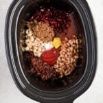 Overhead image of a slow cooker with all of the ingredients for baked beans.