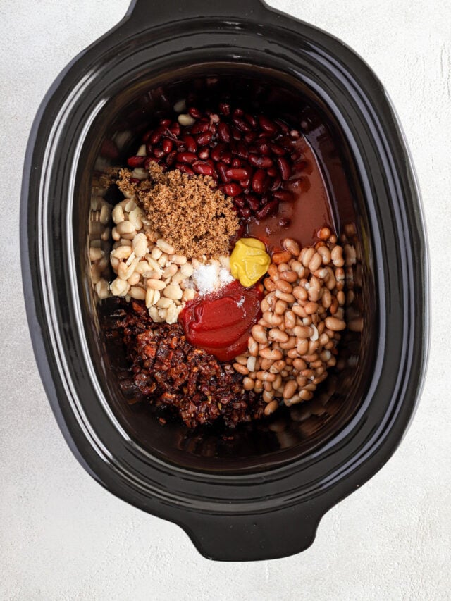 Overhead image of a slow cooker with all of the ingredients for baked beans.