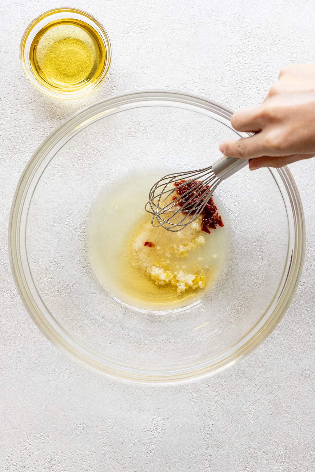 Overhead image of a large bowl with oil, garlic, chipotle, and honey being whisked.