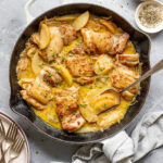 Overhead shot of a skillet with cooked chicken and apples in a pan sauce.