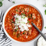 Overhead shot of a bowl of red pepper soup topped with a mound of white rice.