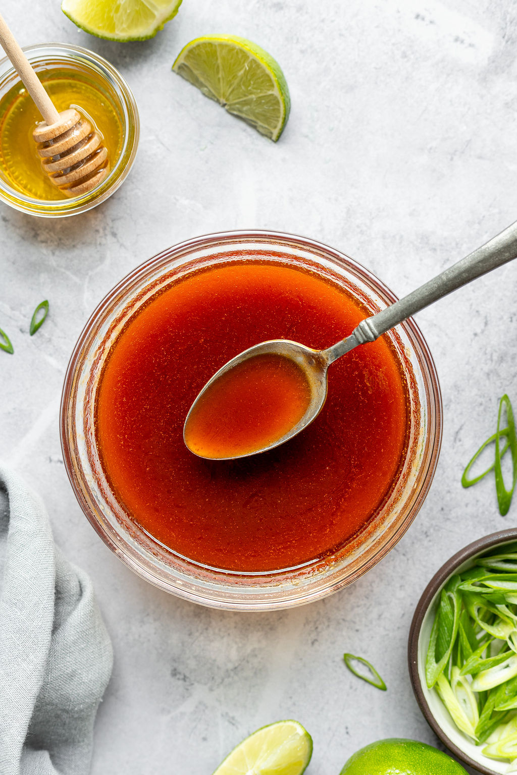 Overhead shot of a red sauce in a small glass bowl with a silver spoon in it.