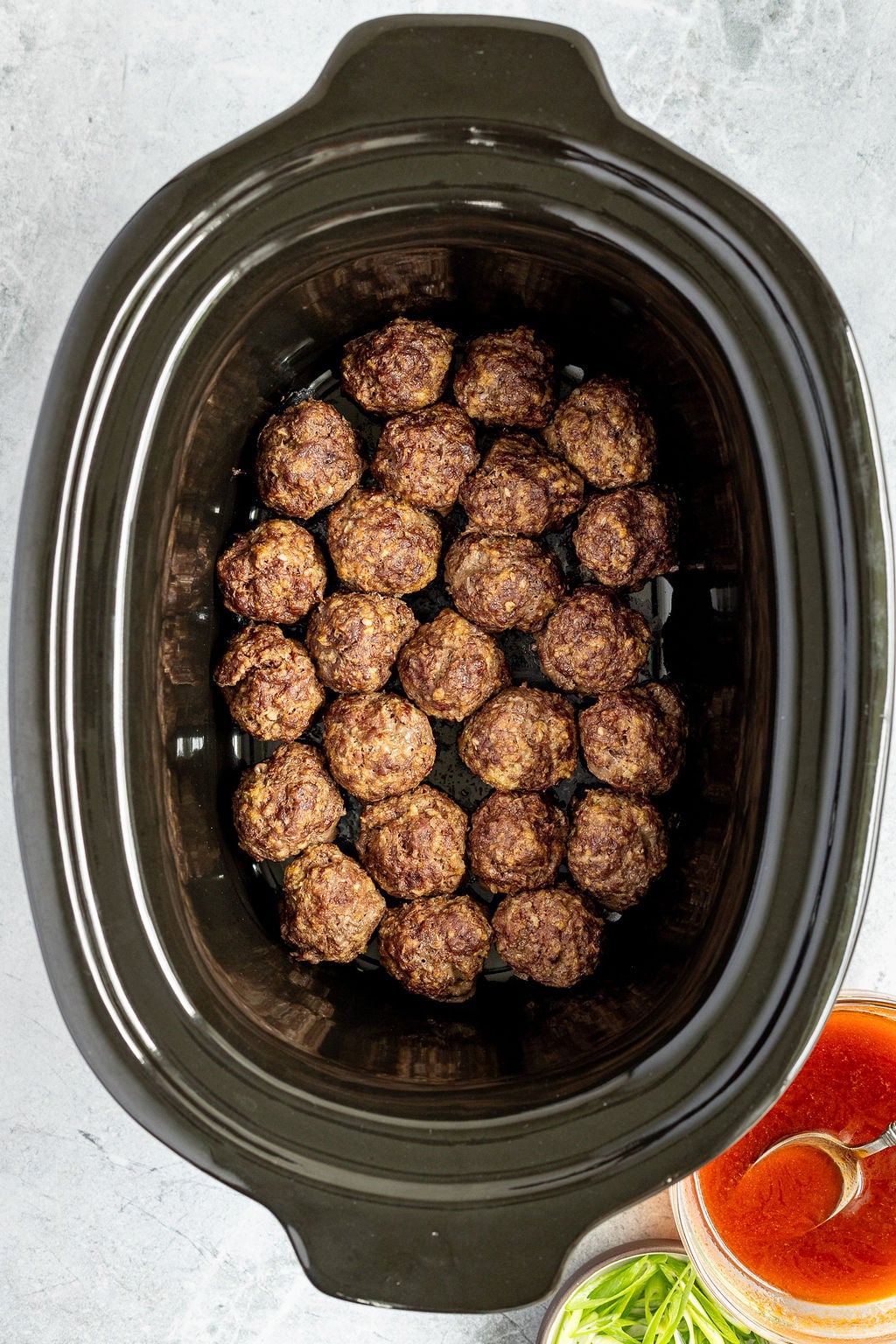 Overhead image of cooked meatballs in a slow cooker.