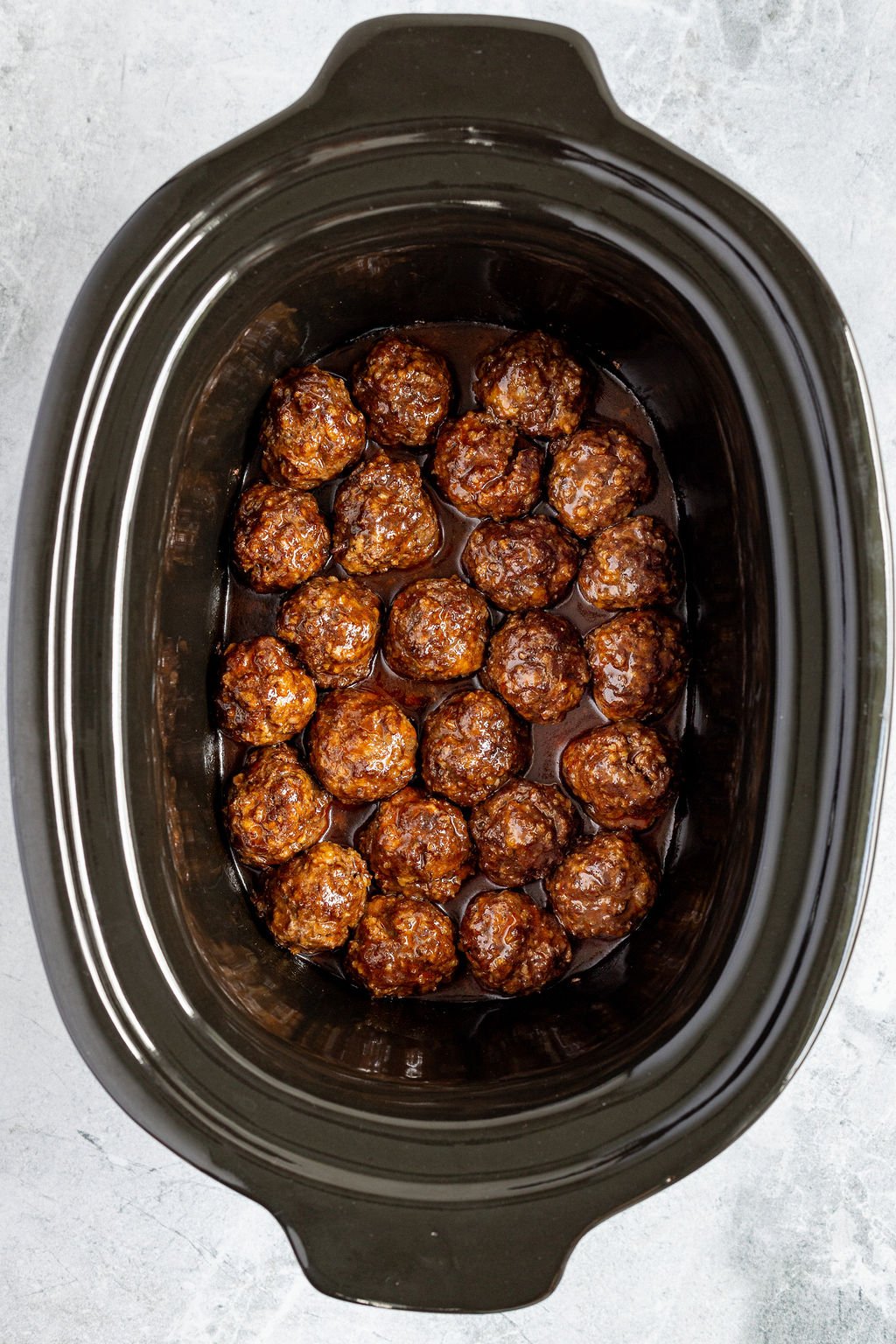 Overhead image of meatballs with sauce in a slow cooker.