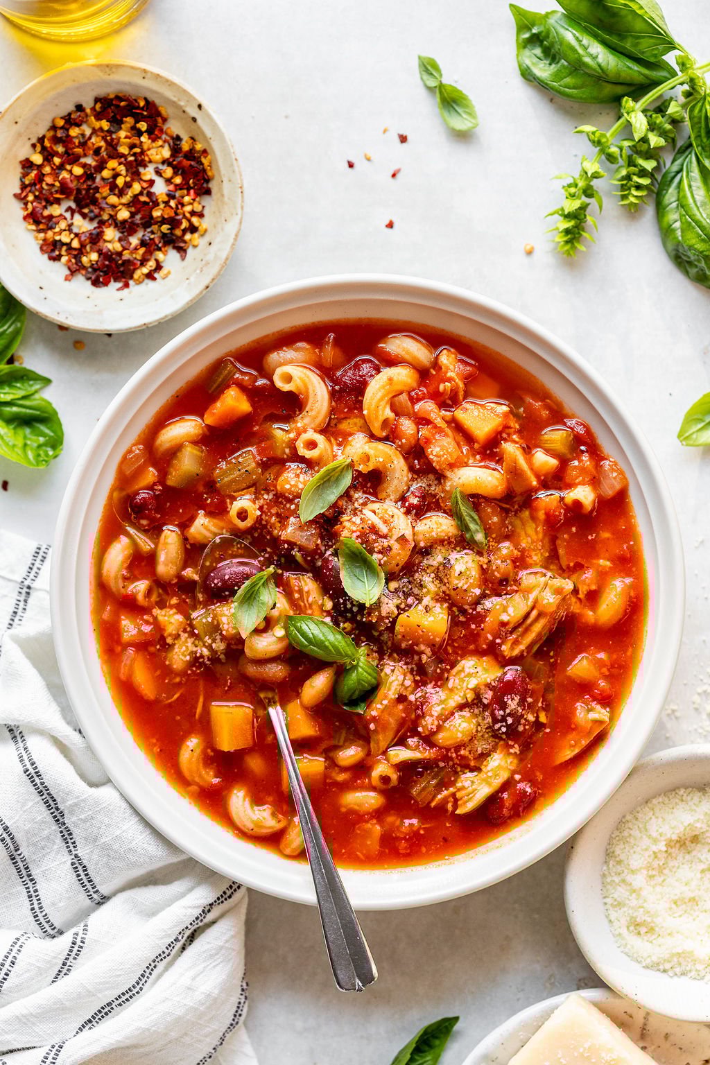 Overhead image of a white bowl with a rad based soup with a spoon in it.