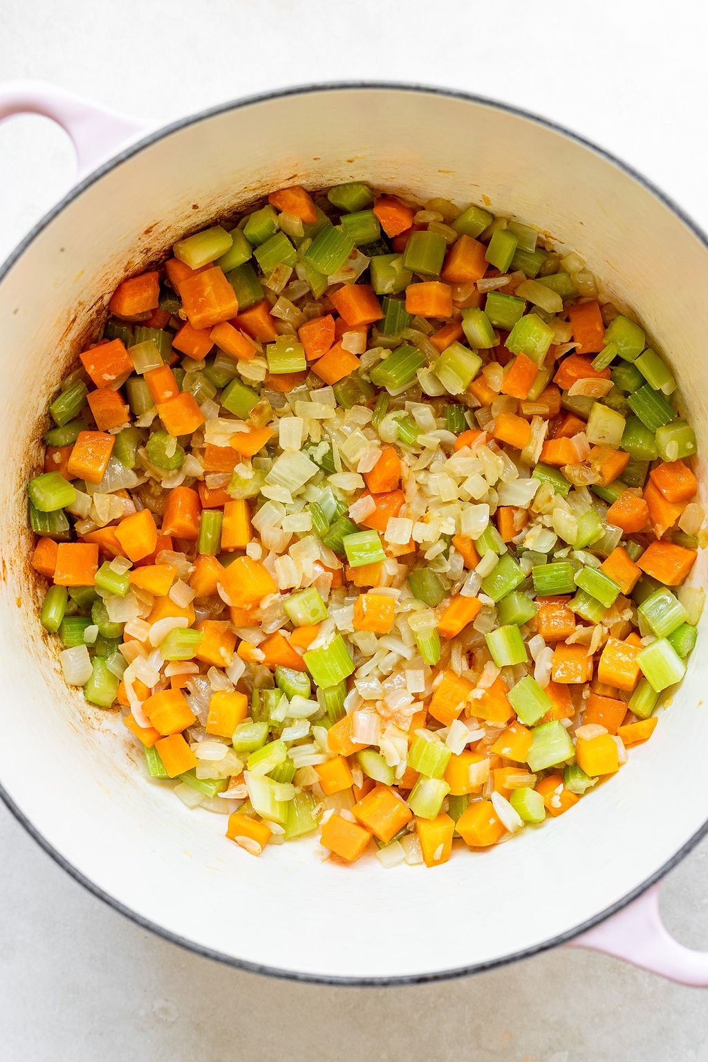 Overhead shot of a pot with cooked onions, celery, and carrots.