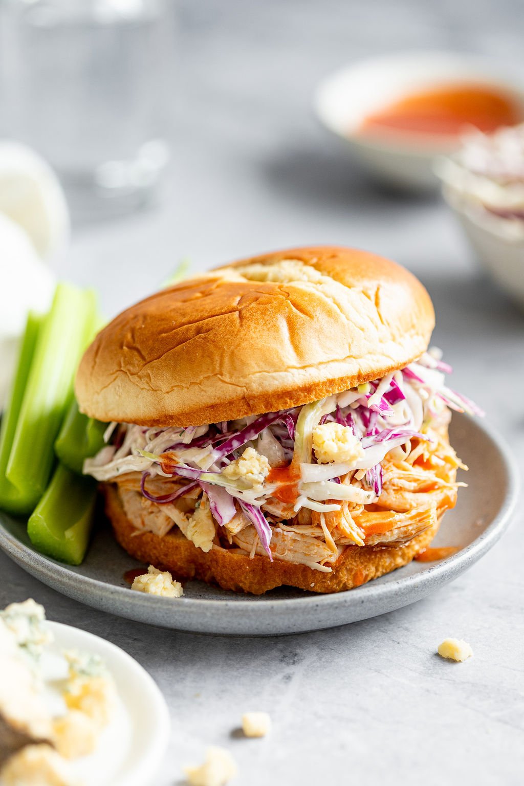 Closeup shot of a buffalo chicken sandwich with coleslaw and celery sticks on the side.