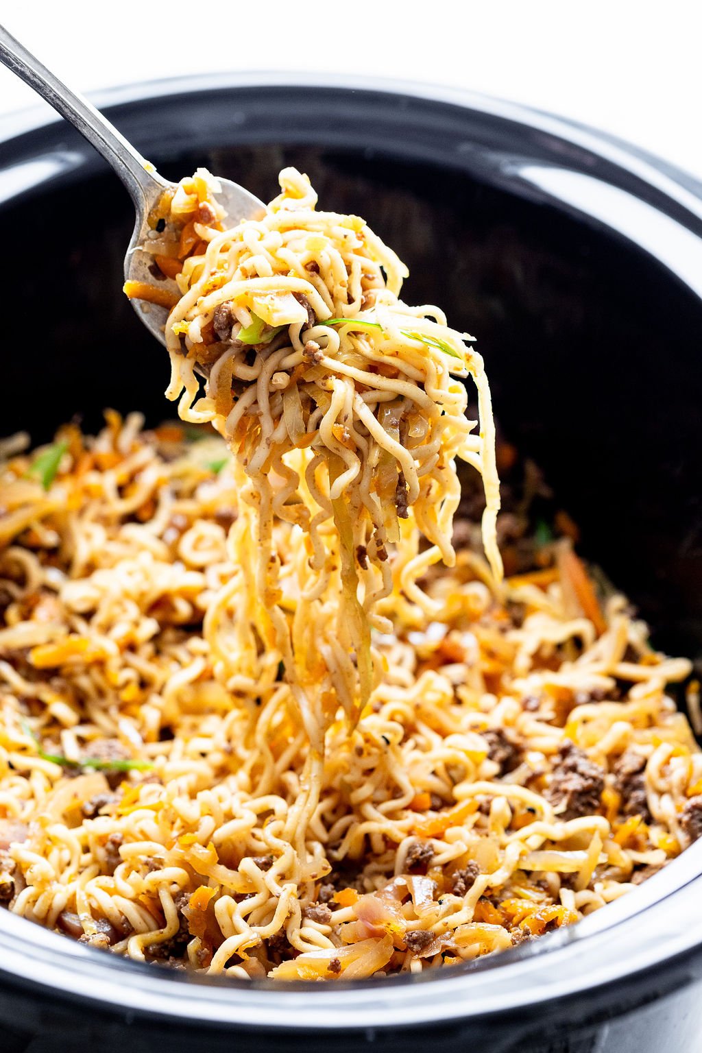 Close up shot of a fork scooping noodles out of a slow cooker.