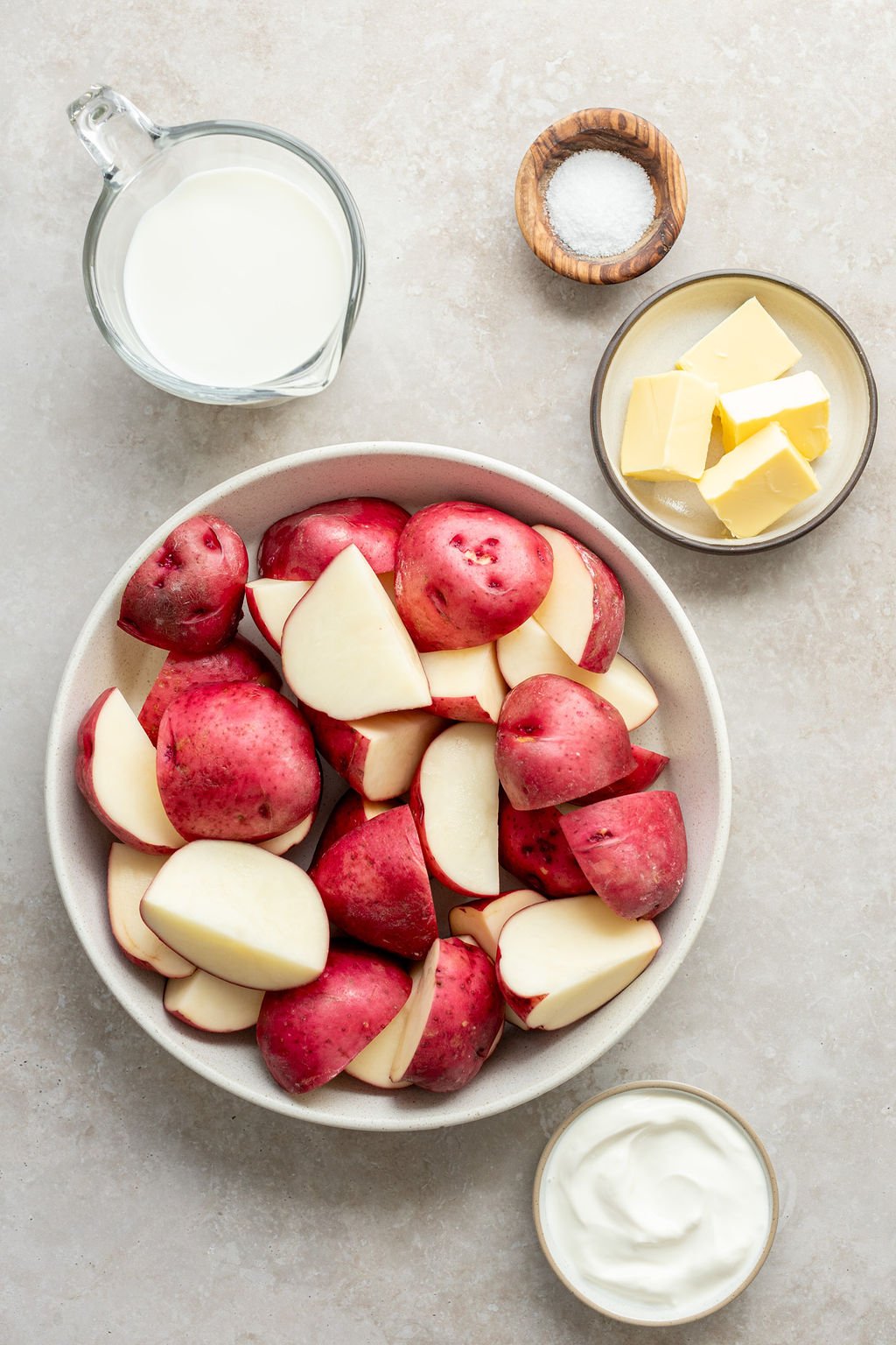 Overhead shot of the following ingredients: milk, salt, butter, raw potatoes, and sour cream.