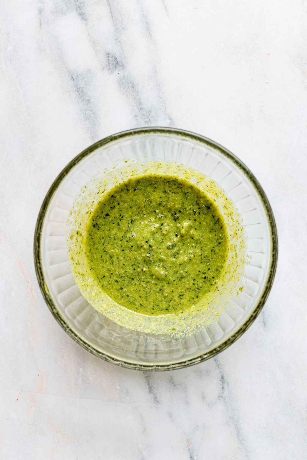 Overhead shot of a glass bowl with green sauce.