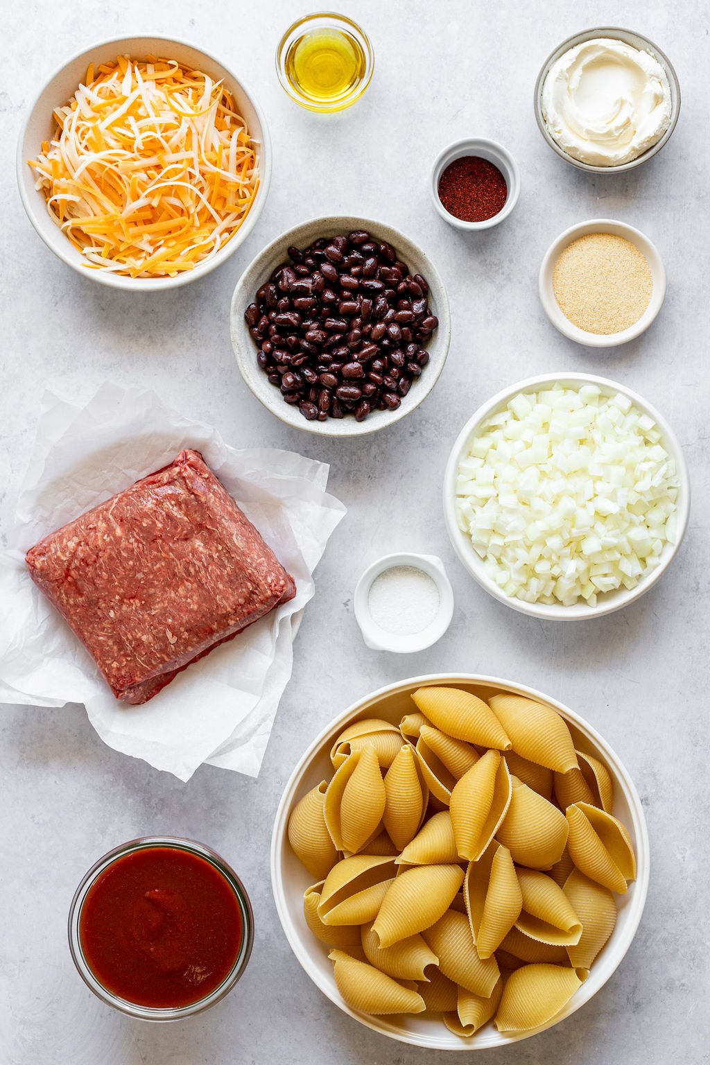 Pasta shells, red sauce, ground beef, black beans, shredded cheese, oil, chili powder, salt, sour cream, garlic powder, chopped onion.