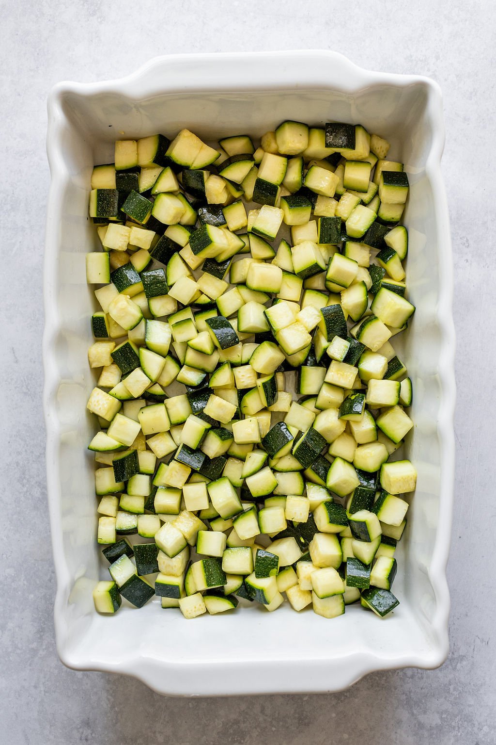 White baking dish with diced zucchini.