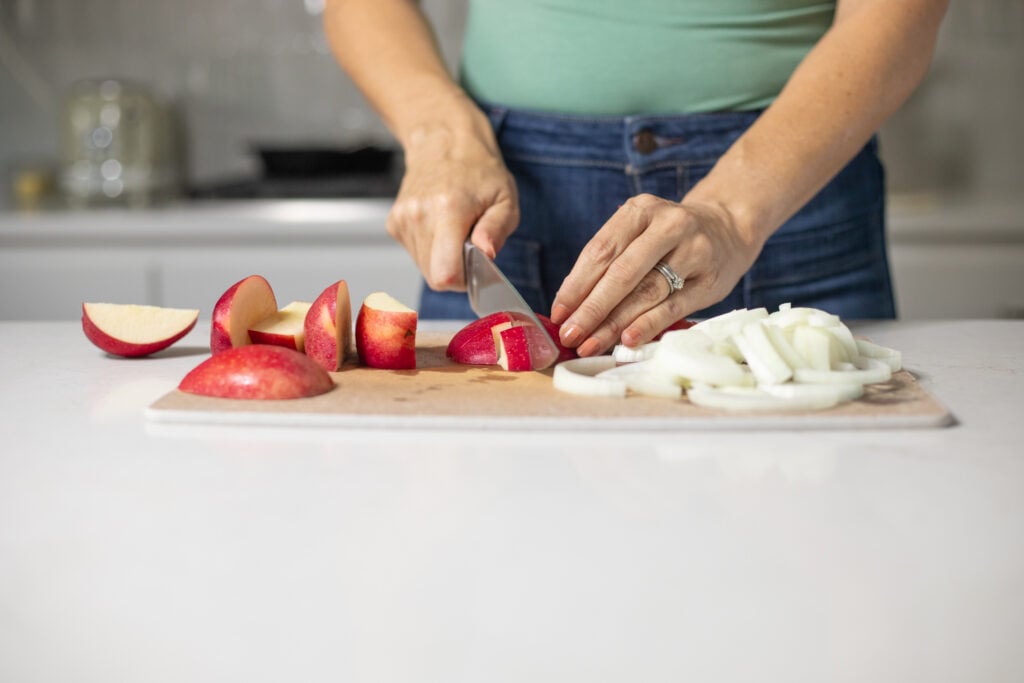 Person chopping apple and onion.