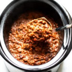 Ladle of chili in a slow cooker of chili.