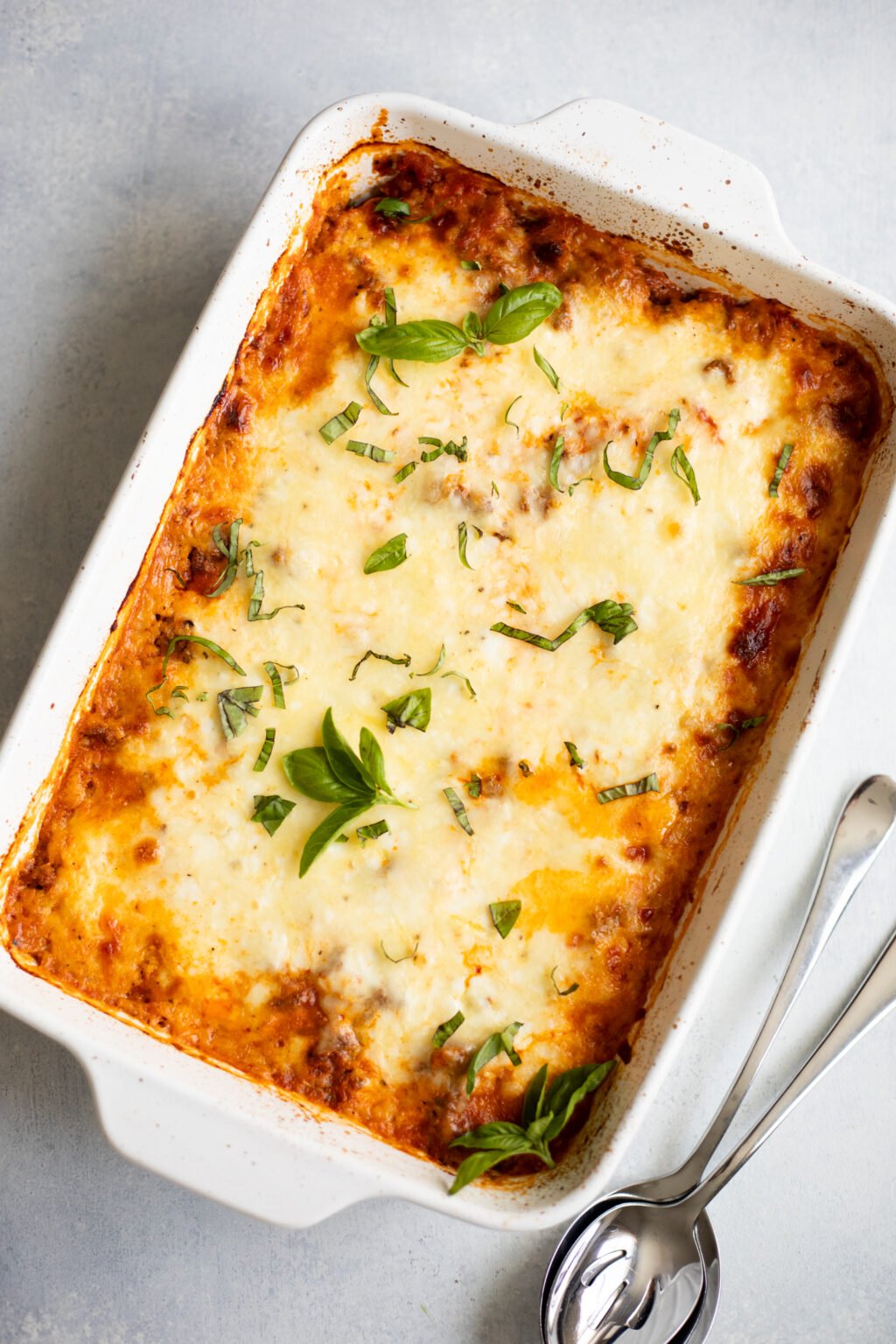 Spaghetti squash casserole topped with basil in a white baking dish.