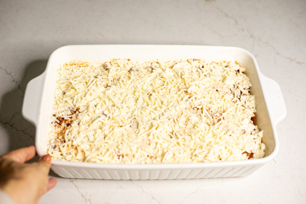 Cheesy tomato casserole topped with cheese in a white baking dish.