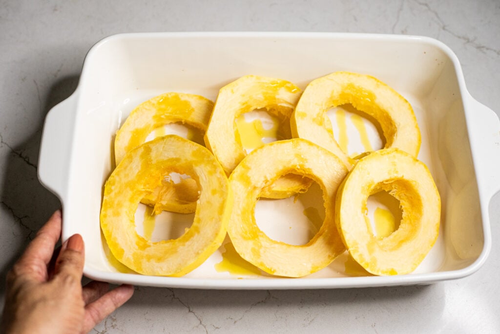 Slices of spaghetti squash in a white baking dish.