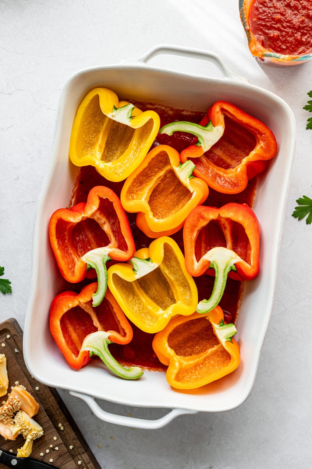 Halved orange, yellow, and red bell peppers in a large casserole dish.