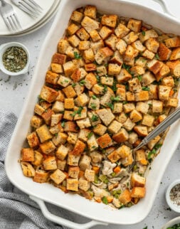 Small cooked bread cubes in a white baking dish topped with parsley.
